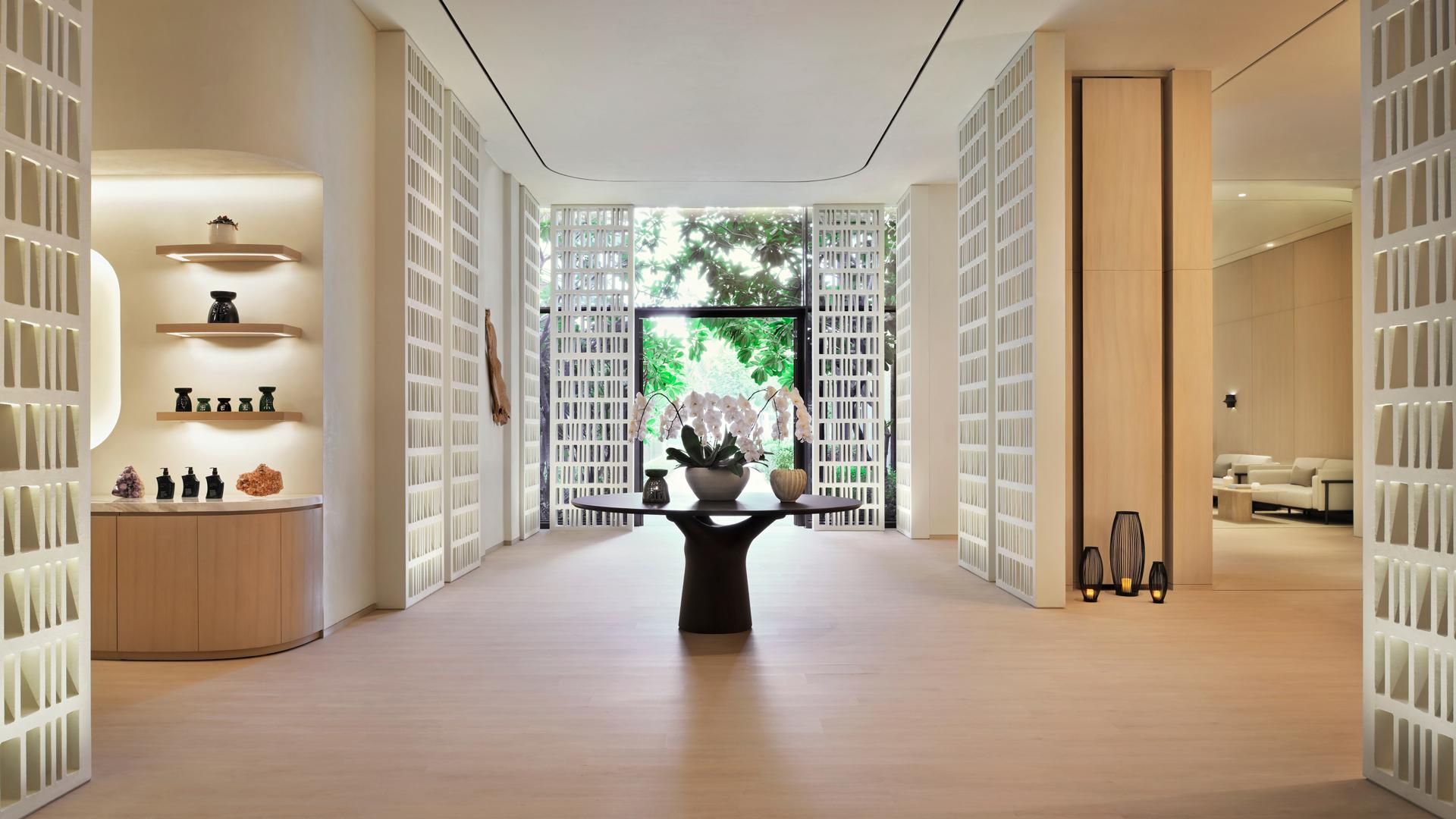 Elegant spa reception area at Banyan Tree Dubai featuring natural wooden interiors, decorative orchids, and curated wellness retail displays with tranquil lighting.