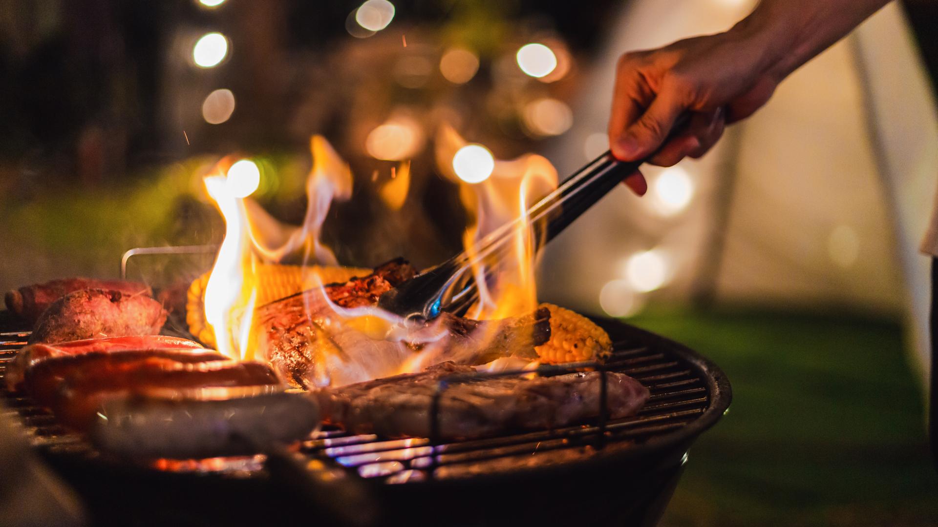 A chef cooks on a flaming barbecue
