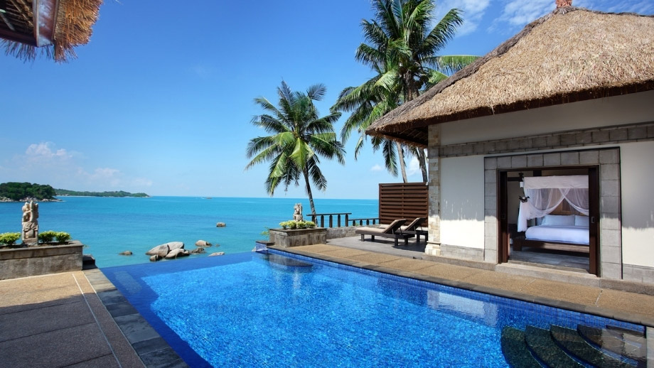Infinity pool overlooks ocean beside villa with palm trees at Banyan Tree Bintan Hotels & Resorts.