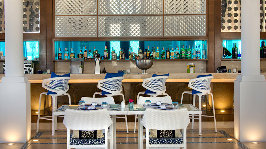 Bar counter displayed with drinks, chairs, and tables in Banyan Tree Tamouda Bay - Azura Restaurant lounge setting.