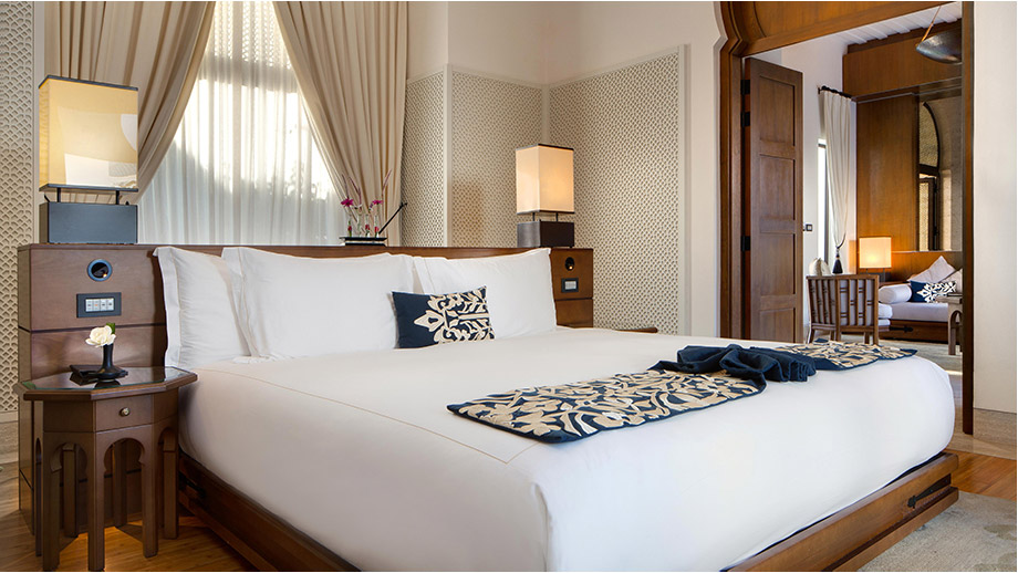 Luxurious bed with elegant linens in Banyan Tree Tamouda Bay Bliss Pool Villa, warm lighting, cozy decor.