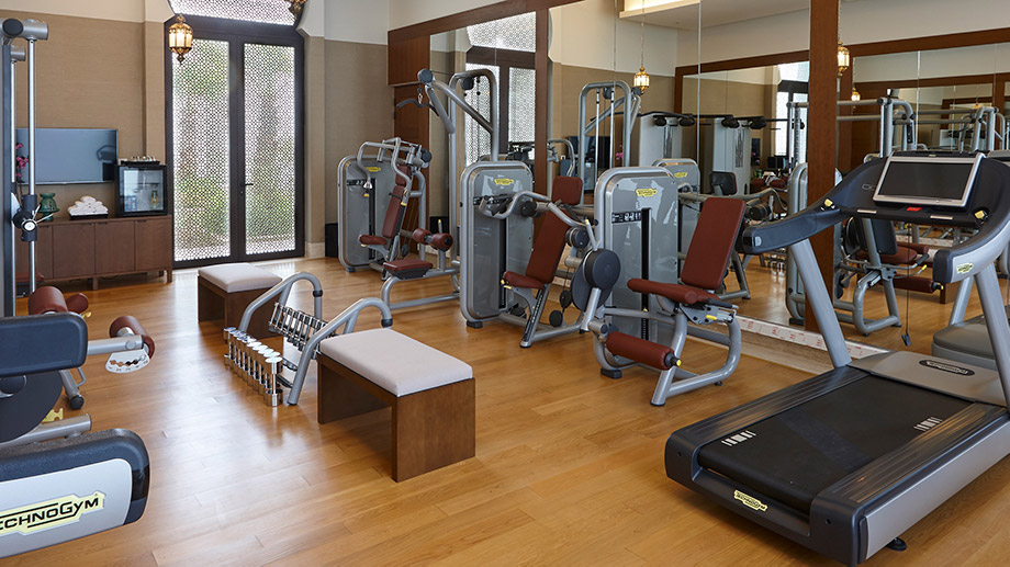 Fitness equipment facilities arranged in a Banyan Tree Tamouda Bay gym with wooden flooring and mirrors.