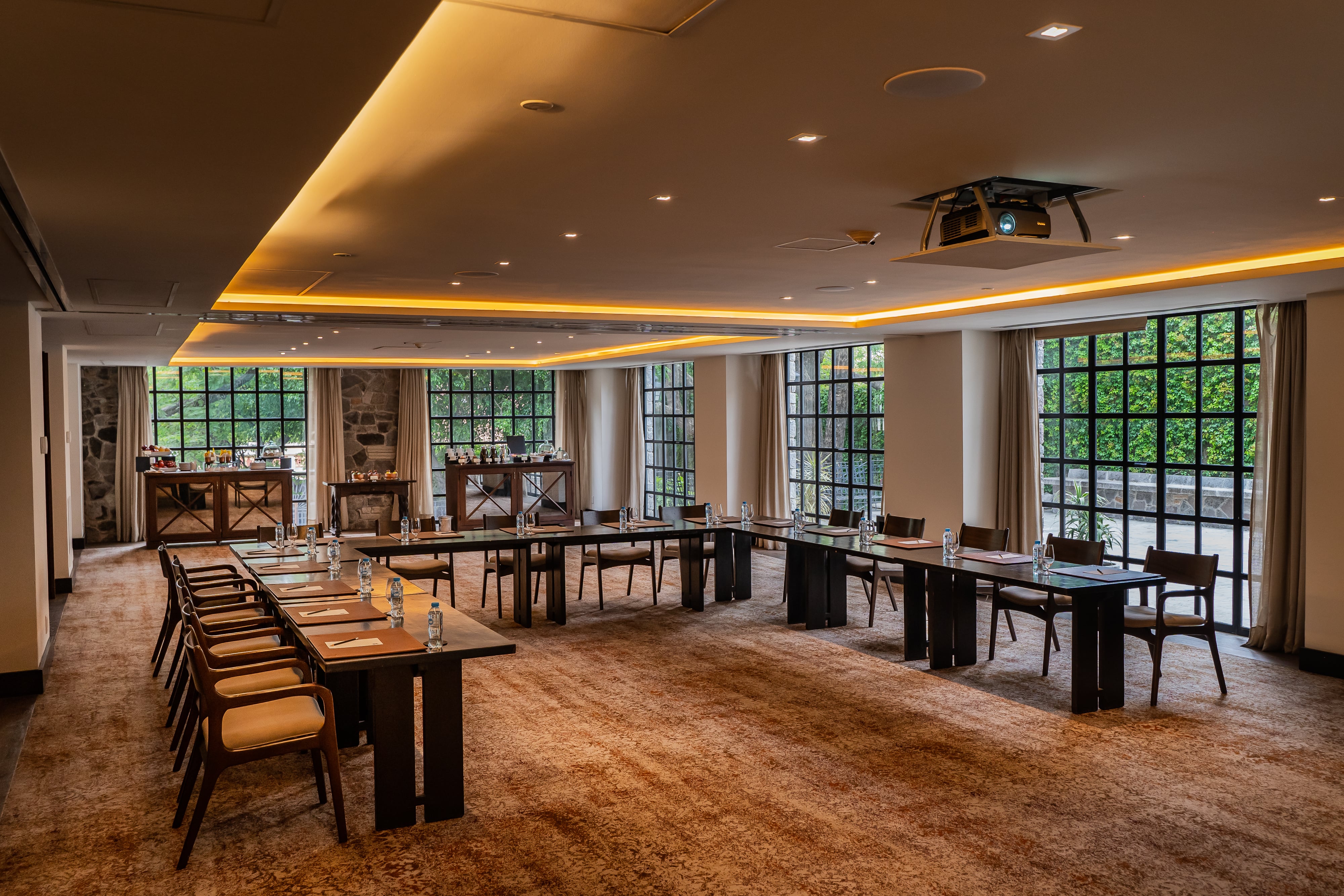 Meeting room setup with U-shaped table arrangement at Banyan Tree Puebla, featuring large windows.