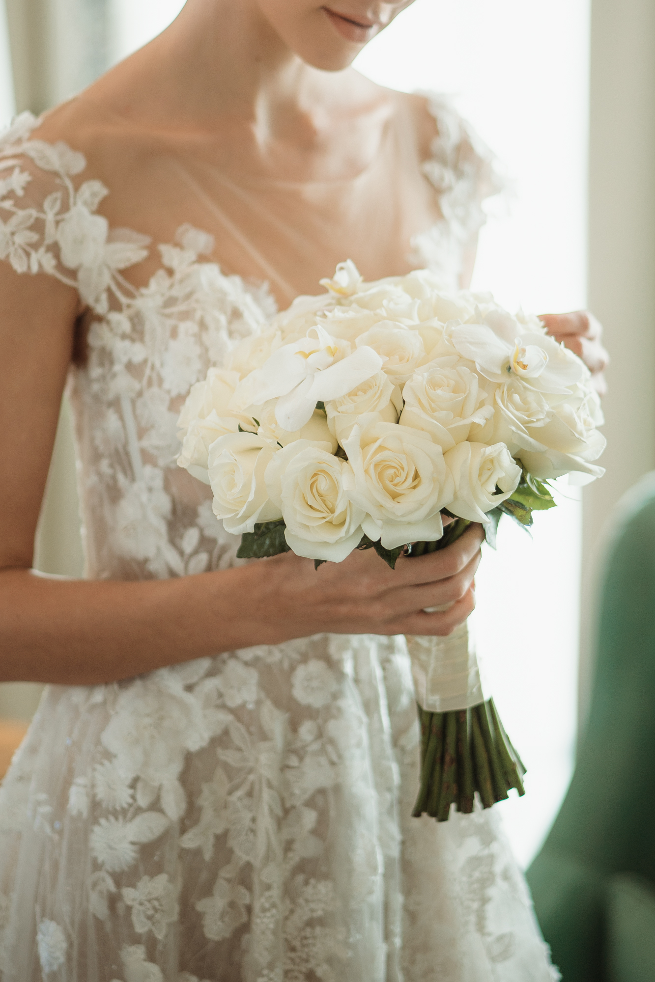 A bride holds white rose bouquet, wearing lace gown; Banyan Tree Puebla.
