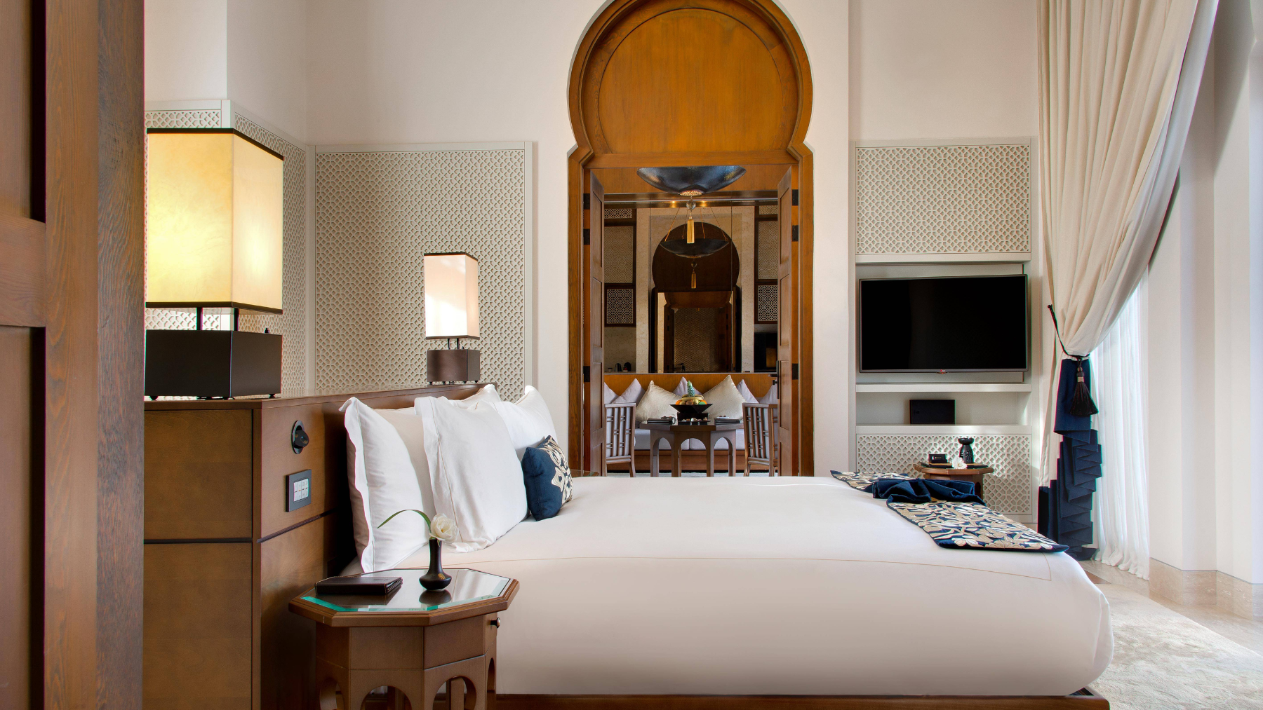 Luxurious bedroom with plush bed, arched doorway, elegant decor in Banyan Tree Tamouda Bay.