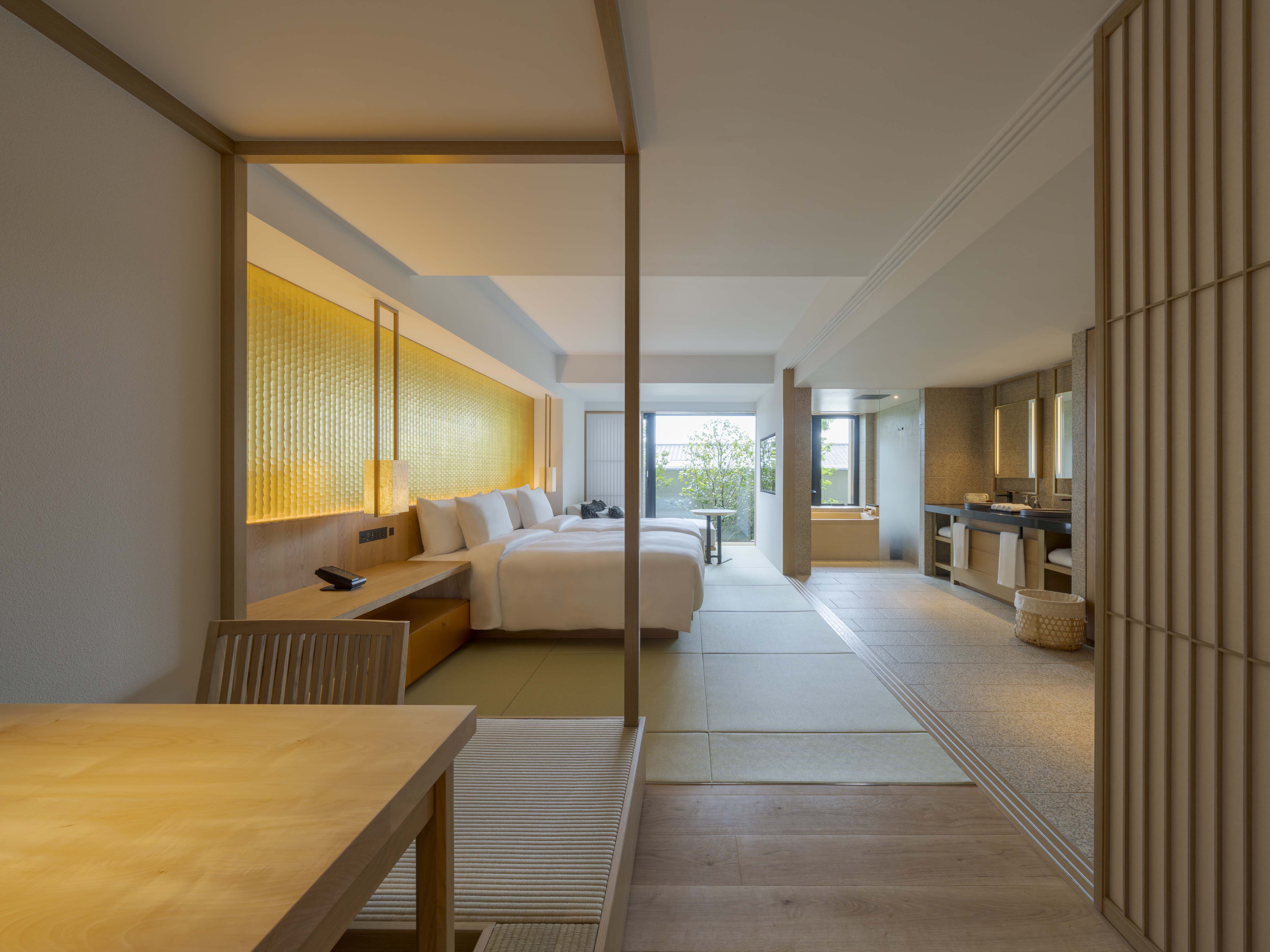 A serene suite at Banyan Tree Higashiyama Kyoto showcases a bed, wood decor, and garden view.