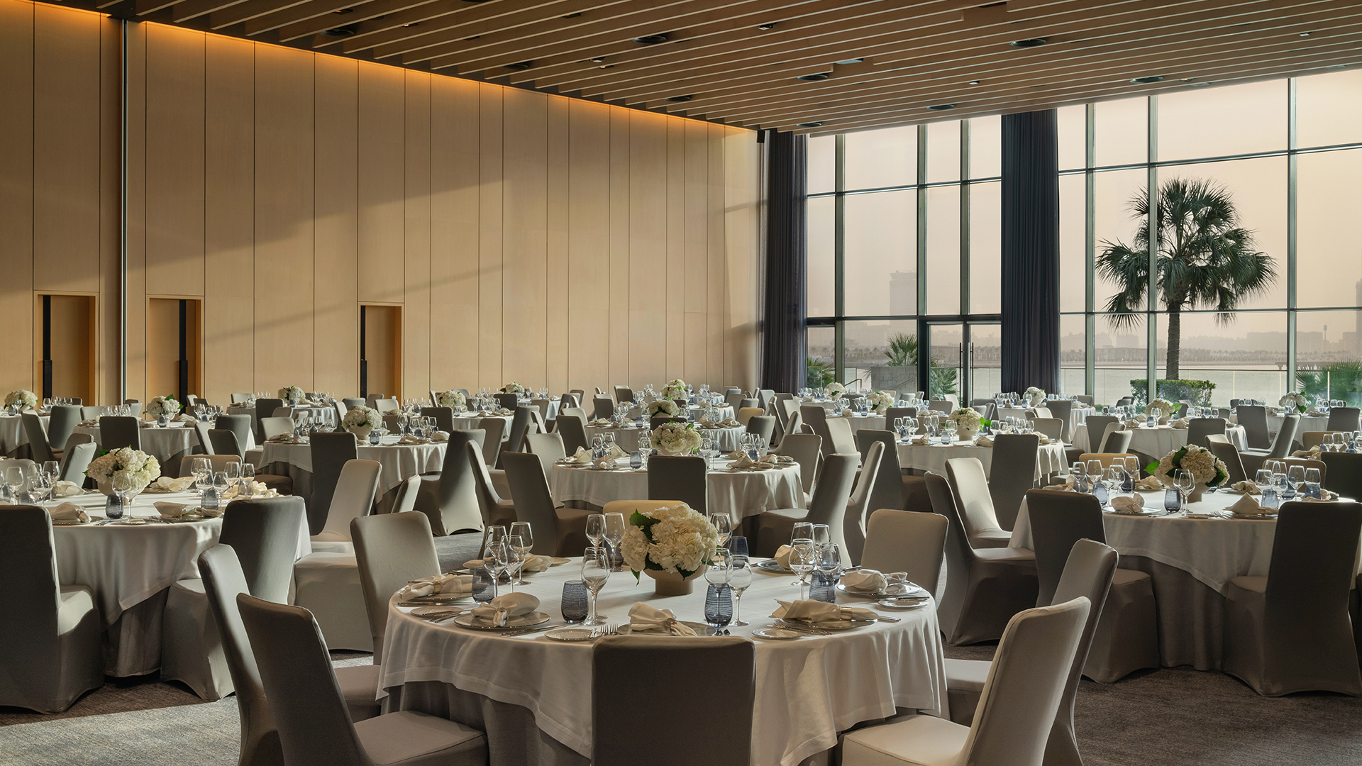 Banquet tables set with white linens; large windows showcasing a view at Banyan Tree Dubai.