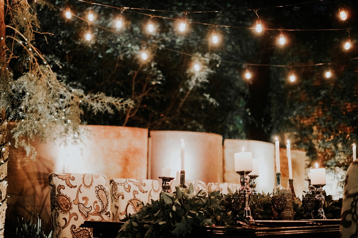 Candles flicker on a table in Banyan Tree Puebla’s garden, under warm string lights.