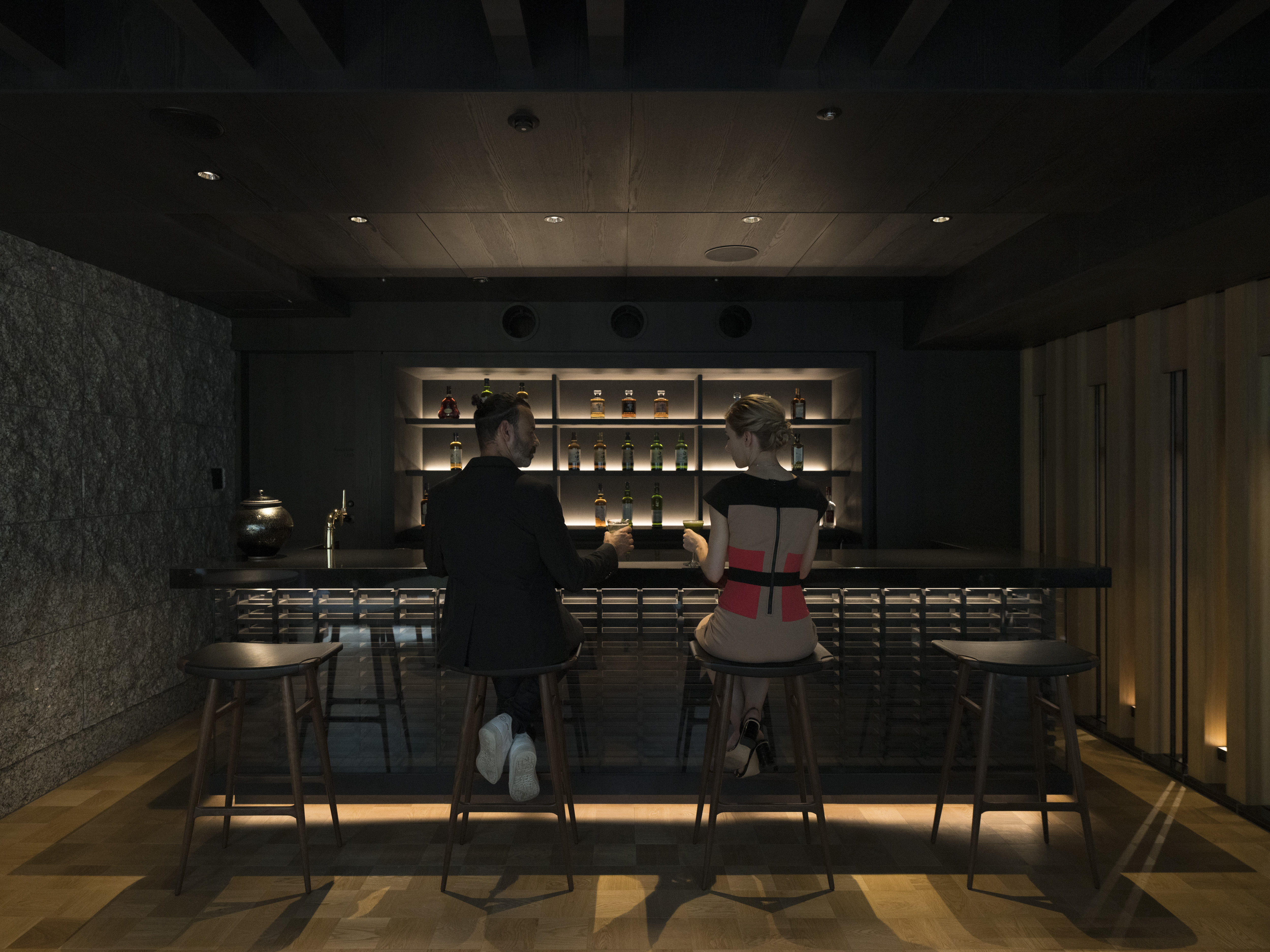 Two people sit at a stylish bar in Banyan Tree Higashiyama Kyoto, engaging in conversation.
