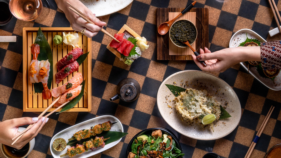 Gohan dining table featuring sushi and Asian dishes being enjoyed, capturing luxury at Banyan Tree Dubai.