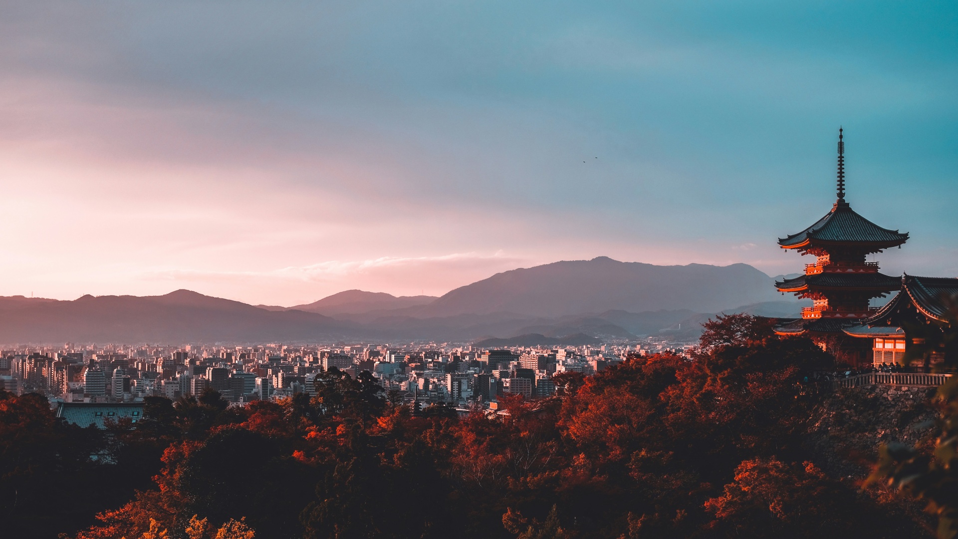 Pagoda overlooks Kyoto cityscape at sunset, framed by autumn trees and distant mountains, Banyan Tree Higashiyama Kyoto.
