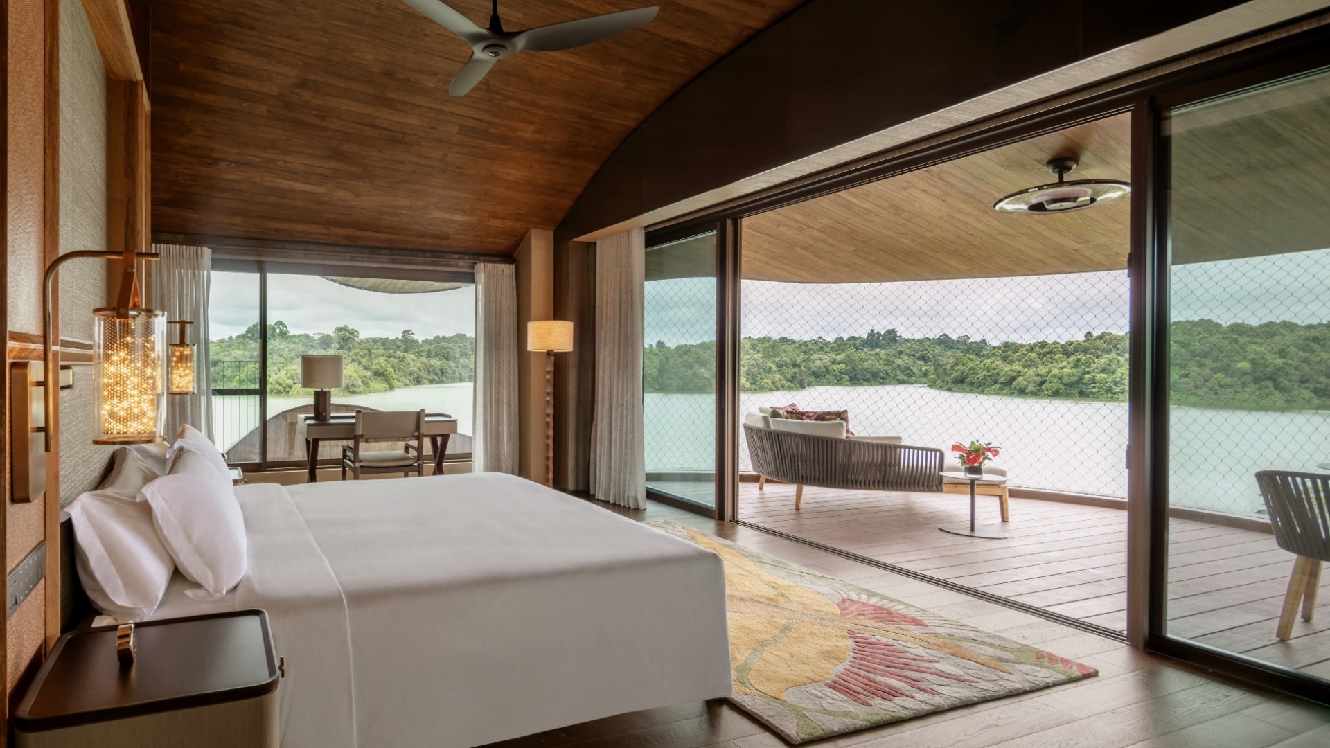 Luxurious treehouse overlooks serene lake, with patio seating; Mandai Rainforest Resort by Banyan Tree.