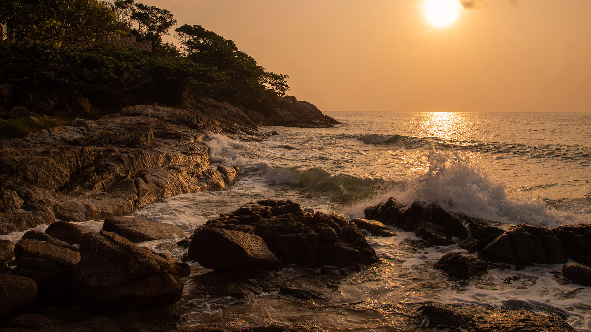 Waves crashing onto a beach at sunset