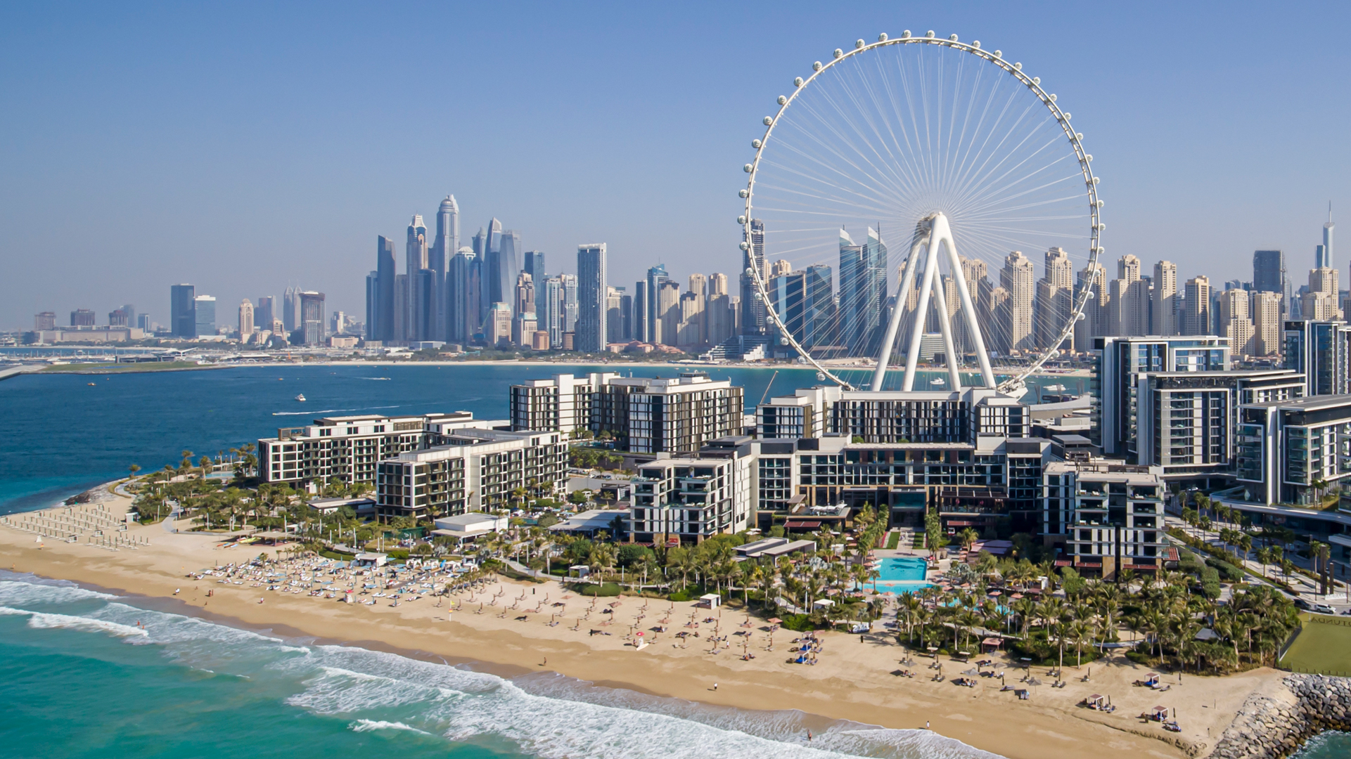 Aerial view of Banyan Tree Dubai on Bluewaters Island, featuring a pristine private beach, Ain Dubai observation wheel, and the iconic Dubai Marina skyline in the background.