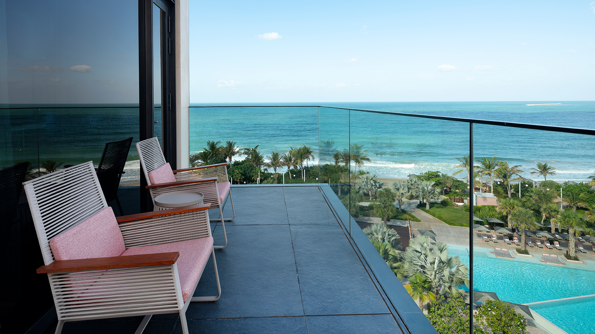 Private balcony at Banyan Tree Dubai’s oceanfront suite overlooking the Arabian Gulf, lush palm gardens, and infinity pool—ideal for serene seaside relaxation.