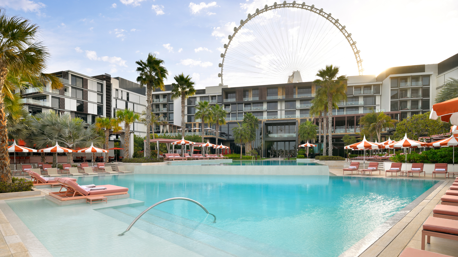Luxury resort pool at Banyan Tree Dubai with sun loungers and parasols, set against the iconic Ain Dubai (Dubai Eye) backdrop.