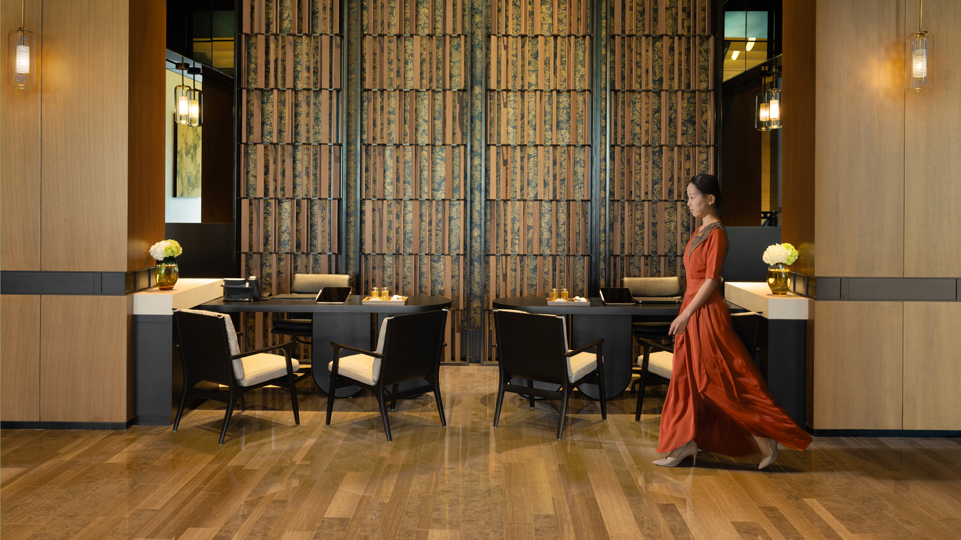Elegant reception area at Banyan Tree Dubai with refined wood-panel interiors, private check-in desks, and a guest in flowing attire, reflecting luxury hospitality and personalised service.