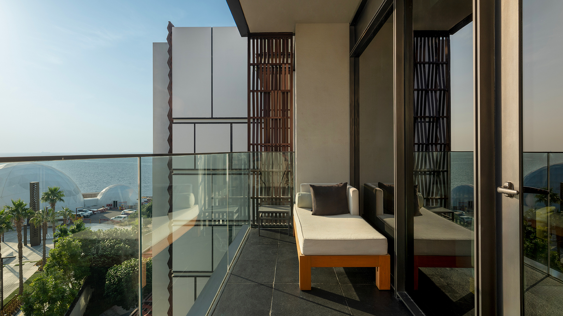 Private balcony at Banyan Tree Dubai’s Bliss Guestroom featuring a plush daybed, modern architectural accents, and partial sea views for tranquil outdoor lounging.