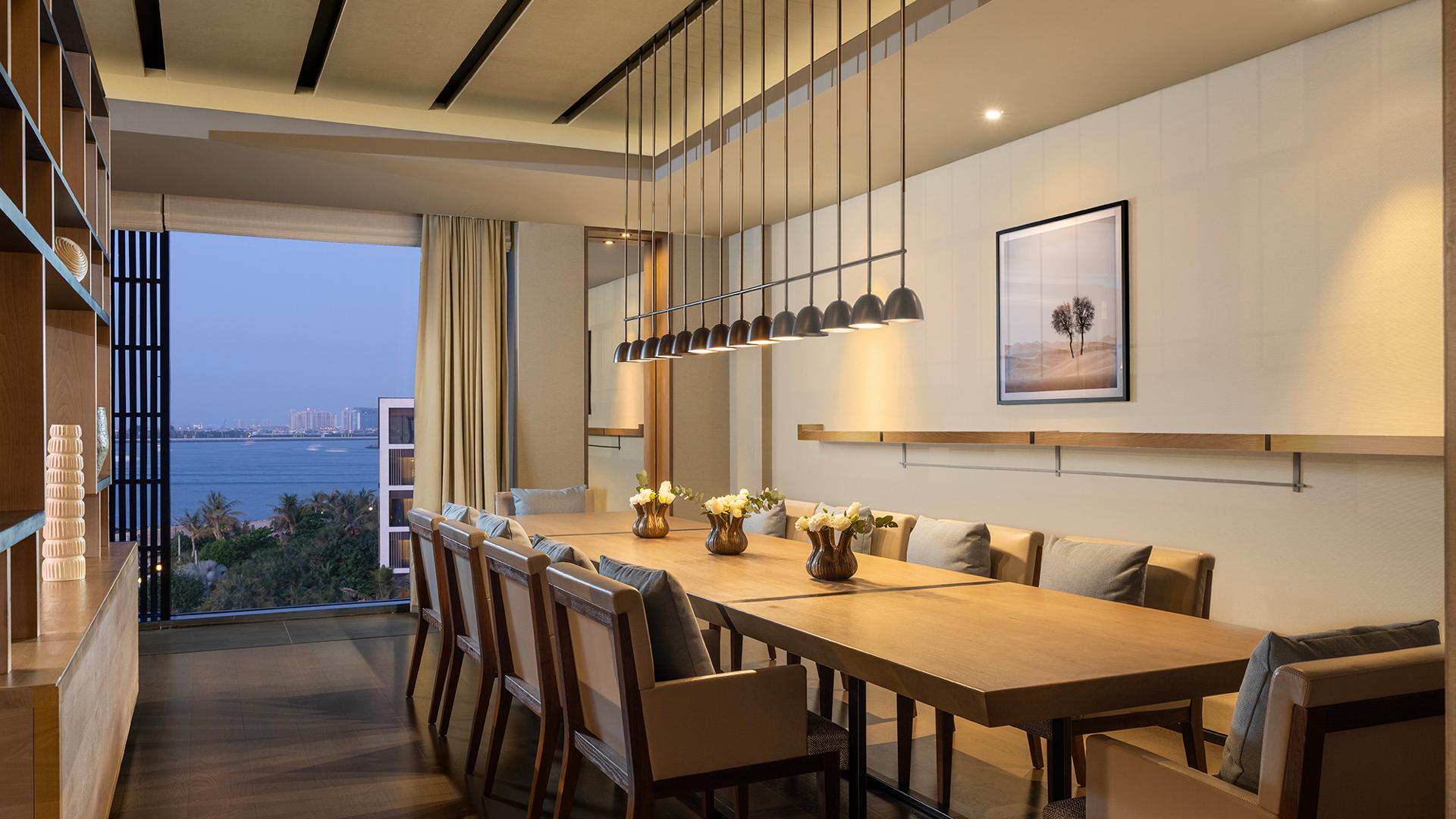 Elegant private dining room in the Harmony Oceanfront Presidential Suite at Banyan Tree Dubai, featuring a long wooden table, ambient lighting, and panoramic sea views.