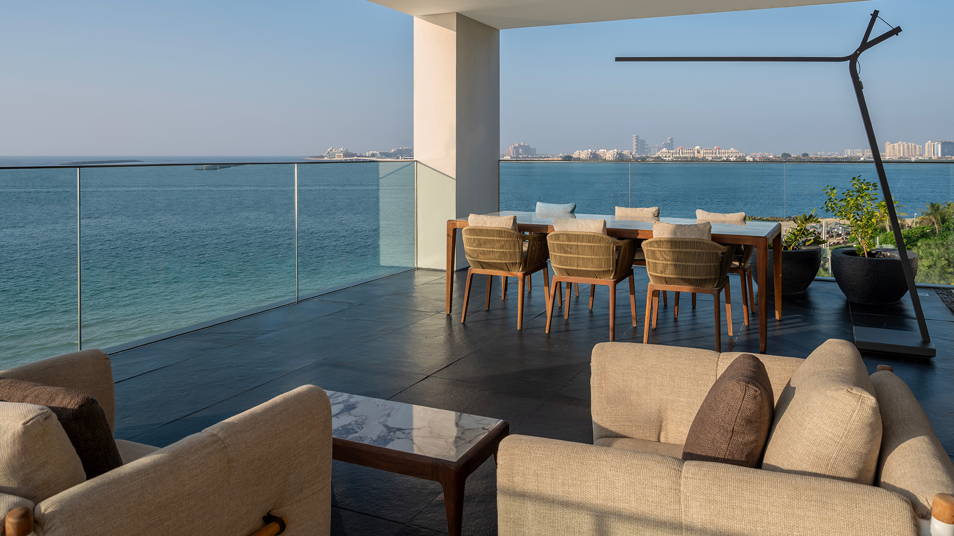 Spacious oceanfront terrace of the Harmony Presidential Suite at Banyan Tree Dubai, featuring an outdoor dining table and lounge area with panoramic views of the Palm Jumeirah.
