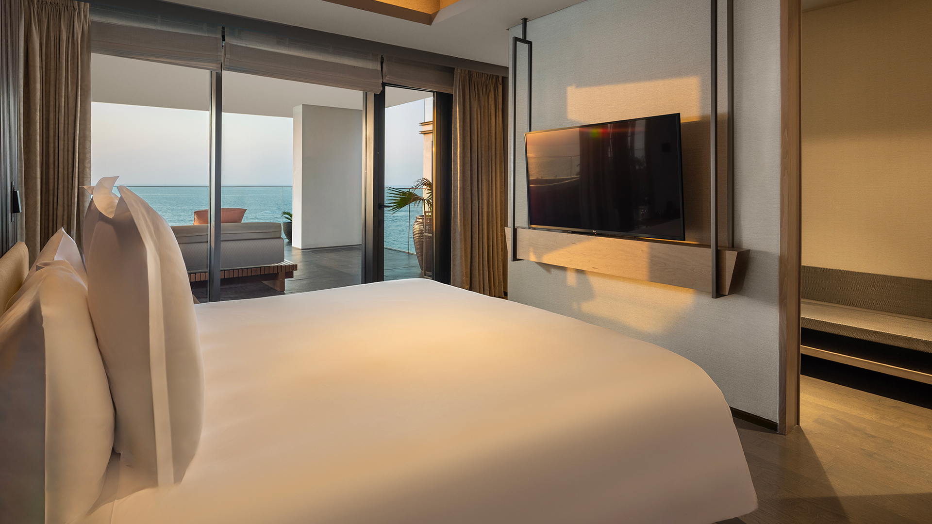 Master bedroom in the Harmony Two-Bedroom Oceanfront Presidential Suite at Banyan Tree Dubai, offering direct terrace access, sea views, and a sleek in-room entertainment setup.