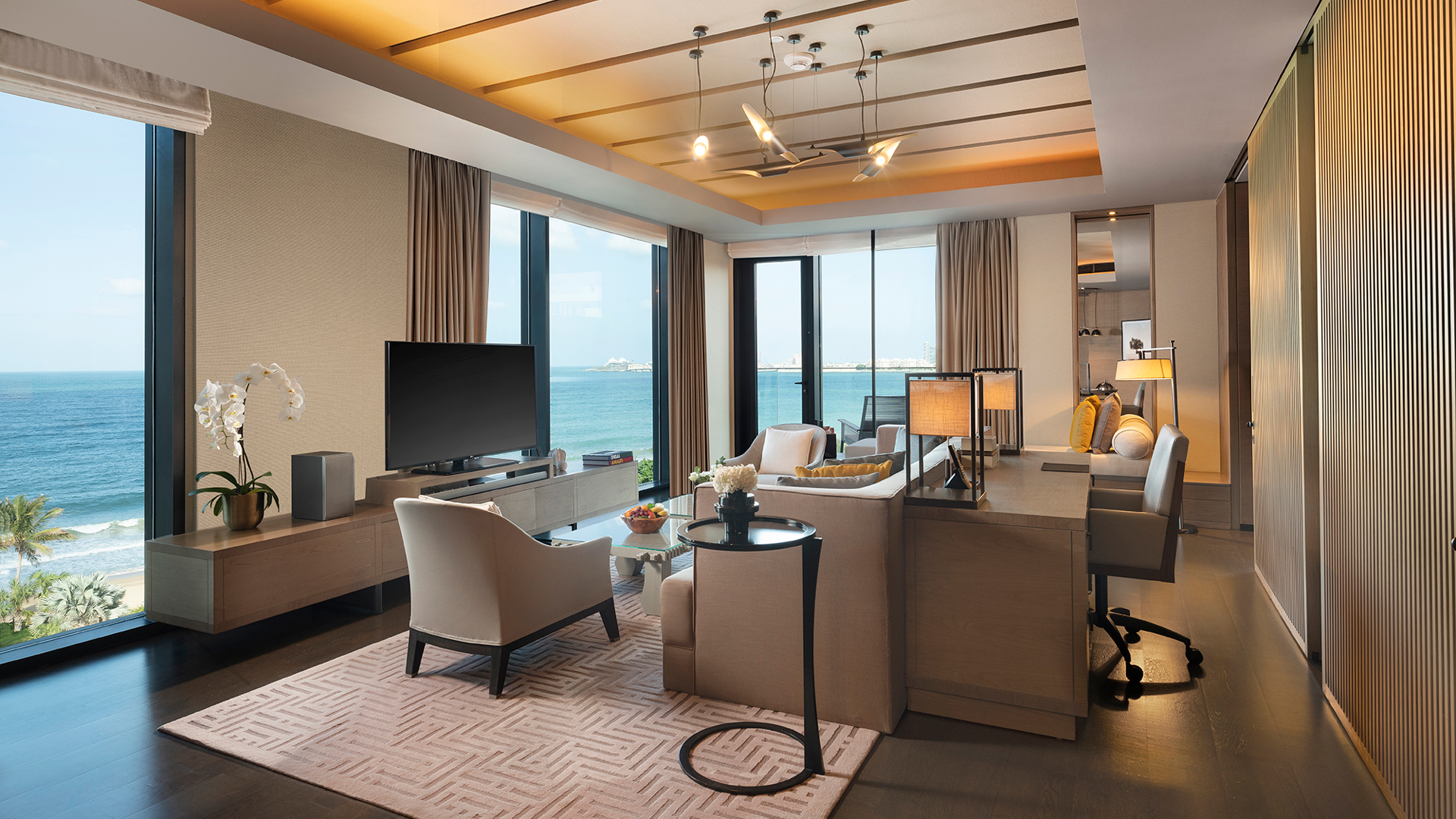 Refined oceanfront living room in the Harmony Master Suite at Banyan Tree Dubai, featuring floor-to-ceiling sea views, modern furnishings, and a private workspace.