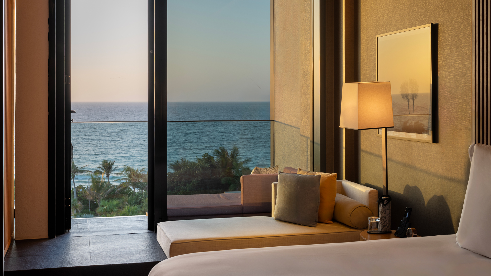 Sunset view from the Serenity Oceanview Guestroom King at Banyan Tree Dubai, featuring a cozy window-side lounge area and uninterrupted vistas of the Arabian Gulf.
