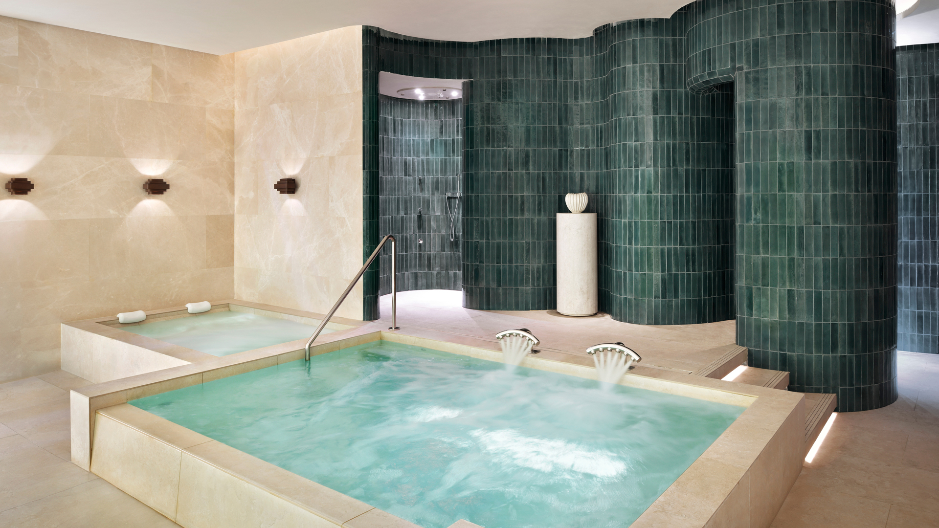 Luxurious spa hydrotherapy area at Banyan Tree Dubai featuring warm plunge pools, overhead water jets, and elegant green-tiled walls designed for wellness and relaxation.
