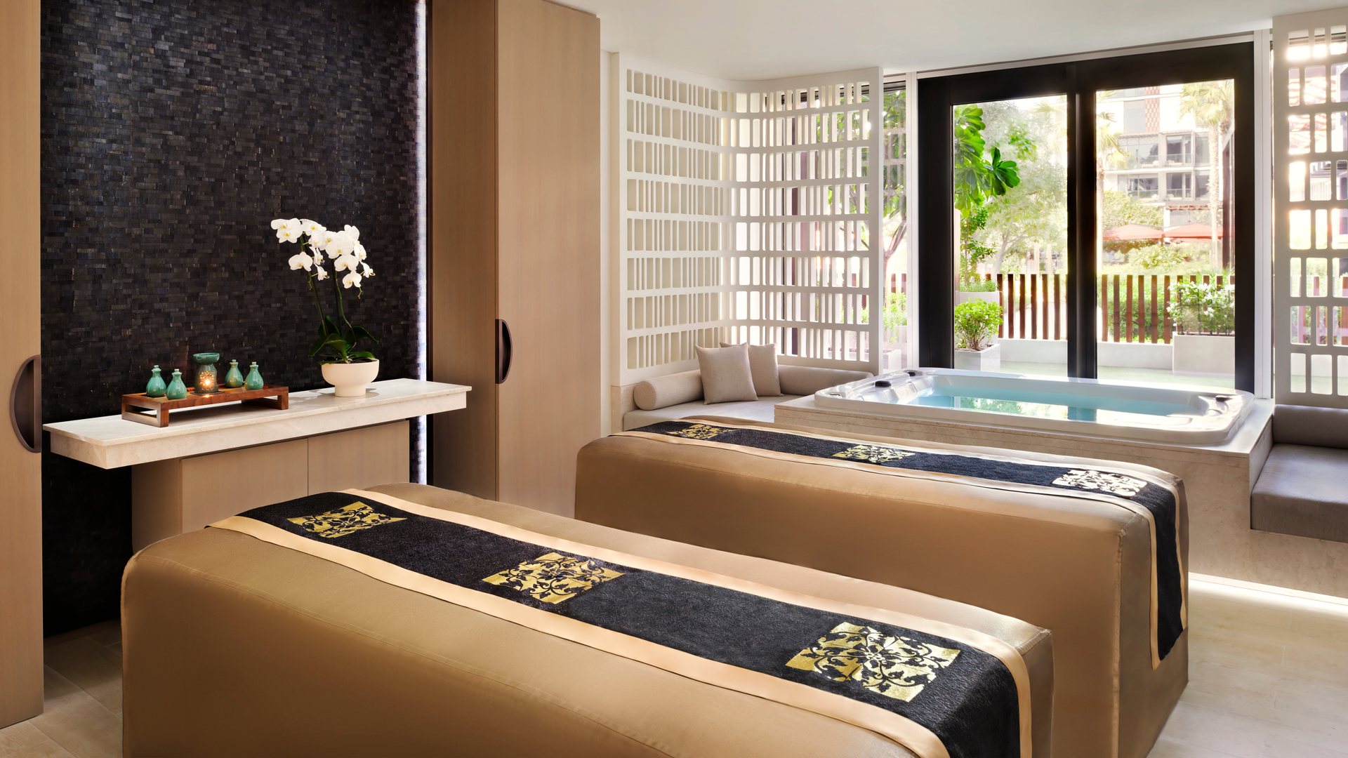 Luxurious spa suite at Banyan Tree Dubai featuring twin massage beds, elegant orchid décor, and a private Jacuzzi with natural daylight.