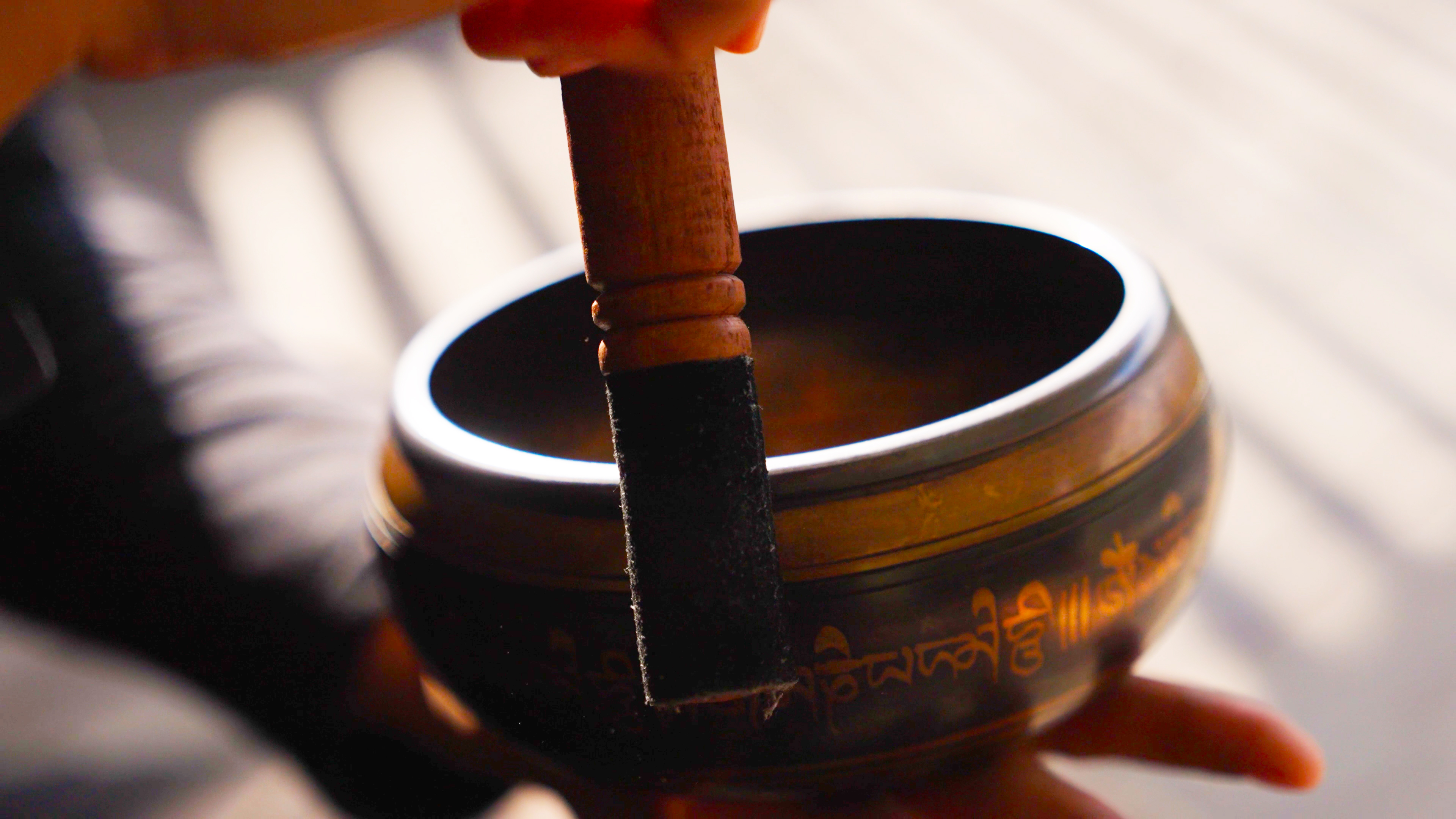 Close-up of a singing bowl being played with a wooden mallet during a sound healing ritual.