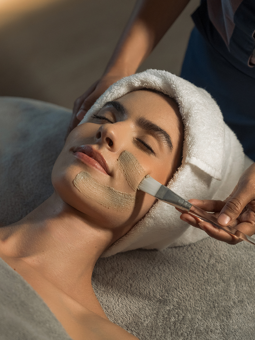 Spa therapist applying a soothing facial mask to a guest’s face during a relaxation treatment.